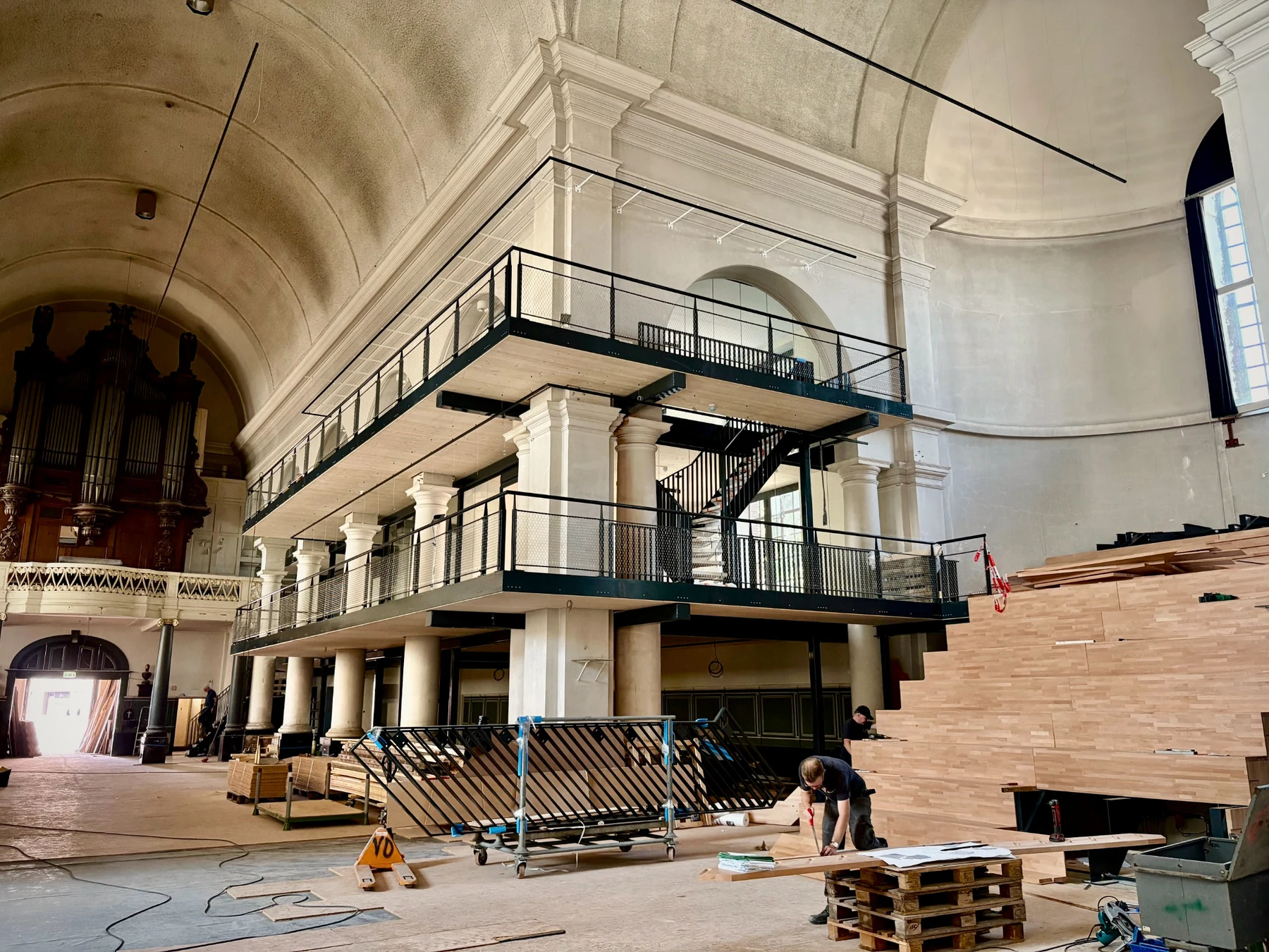 Nieuwe stalen galerijen en houten tribune binnen de monumentale kolommen en gewelven van de Sint-Jan