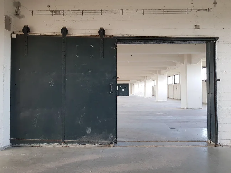 Open industriële schuifdeur naar een lege verdieping van het HAKA-gebouw