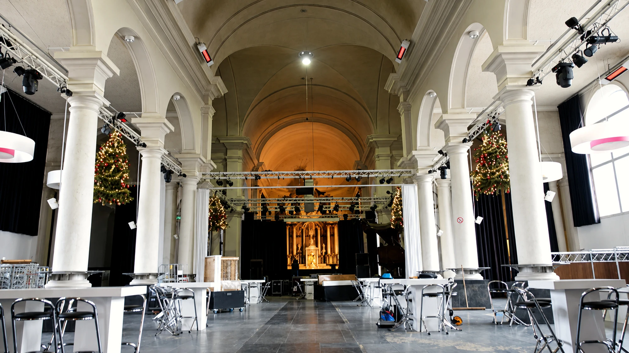 Het kerkinterieur van de Sint-Jan vóór de huidige ingrepen, met statafels, licht en truss tussen de witte kolommen