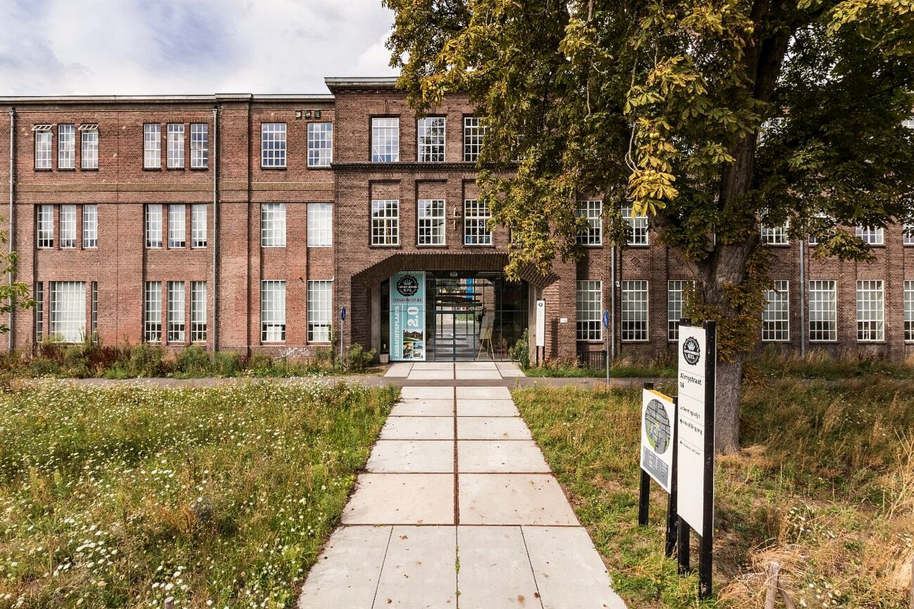 Entree van de KVL fabriek tussen het historische metselwerk en het groene fabrieksterrein
