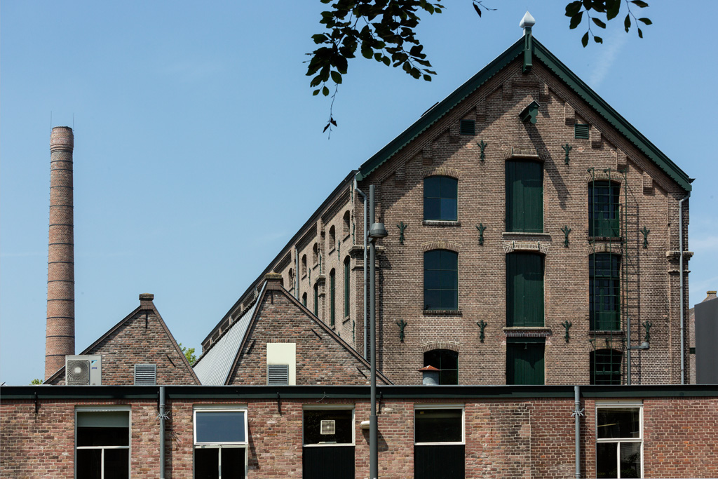 Bakstenen fabrieksdaken, schoorsteen en gevel van het historische Tilburgse textielcomplex
