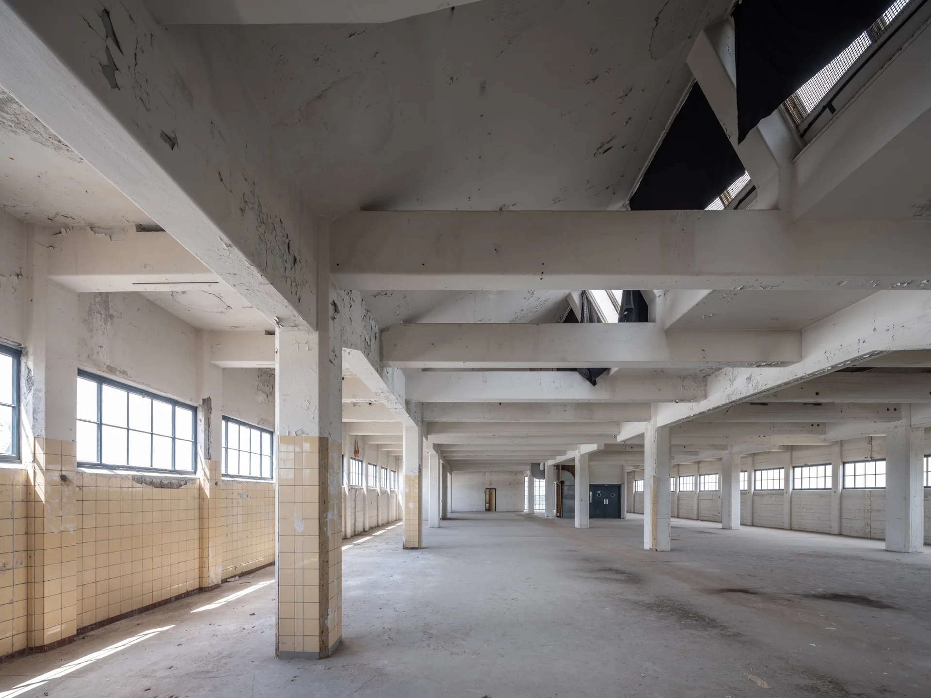 Lege industriële verdieping in het HAKA-gebouw met betonnen kolommen en tegelwanden